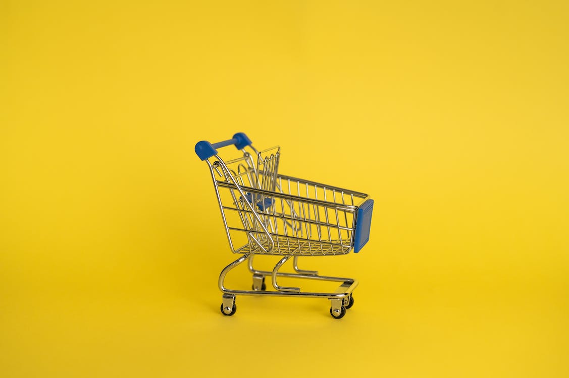 A small shopping trolley on a yellow background
